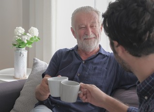 Happy smile old caucasian man drinking coffee with son in living room house