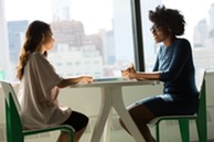 Two women sitting across from each other at a table and talking.