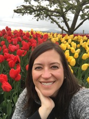 Molly Nolan-Jones smiling and standing in front of bright red and yellow tulips.