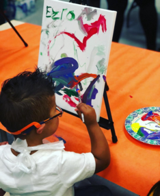 photo of a boy that is painting on a canvas 