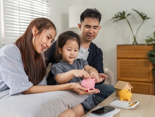 Family engaging in savings activities with a child, using a piggy bank and financial planning tools