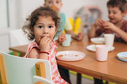 Young girl eats apple at table.