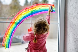 little toddler girl with rainbow painted with colorful window color