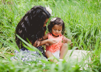 photo of two sisters sitting down on the grass talking 