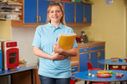 Woman holding folder standing in child care classroom.