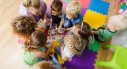 Woman with children on floor in classroom.