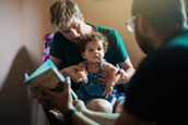 Two dads read to their curious baby.