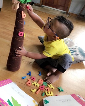 photo of a boy wearing glasses playing with an alphabet tree