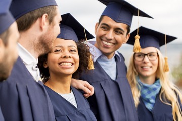 group of kids in graduation caps and gowns smiling at each other outside