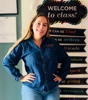 Woman with dark long hair stands in classroom.