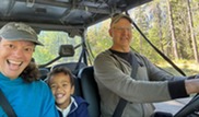 Young boy sits in front seat between adult man and woman.
