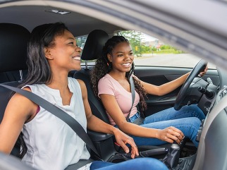 Young black teenage driver seated in her new car with her mother