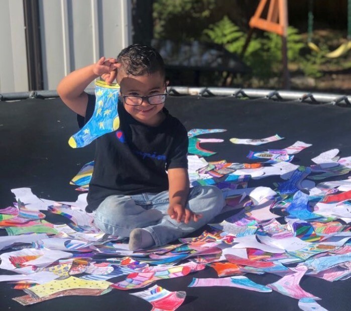 boy that has down syndrome that is hold paper socks that are colored representing DS
