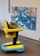 Photo of a mini explorer, a stuffed green dinosaur sits in the baby seat.