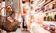 Person holding basket in grocery store.