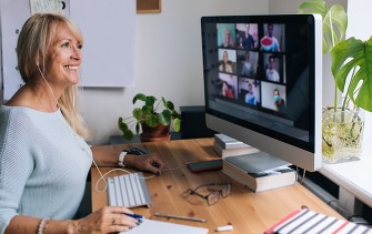 Smiling mature woman having video call via computer in the home office. 