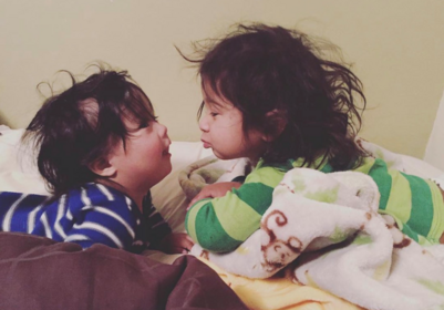 Two little ones share a sweet, playful moment — messy hair, cozy pajamas, and smiles full of love.