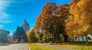 Capitol building in fall with orange and yellow leaves in trees and on ground.