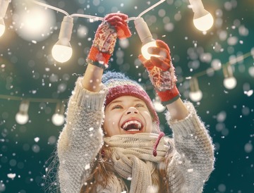 little girl in the snow smiling at holiday lights