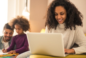 dad and daughter drawing together, mom on the couch working on a computer