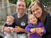 A family photo of Lindsey and her husband smiling, holding their smiling toddler daughter and baby son.