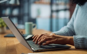 Close Up on Hands of a Female Specialist Working on Laptop Computer at Cozy Home Living Room while Sitting at a Table