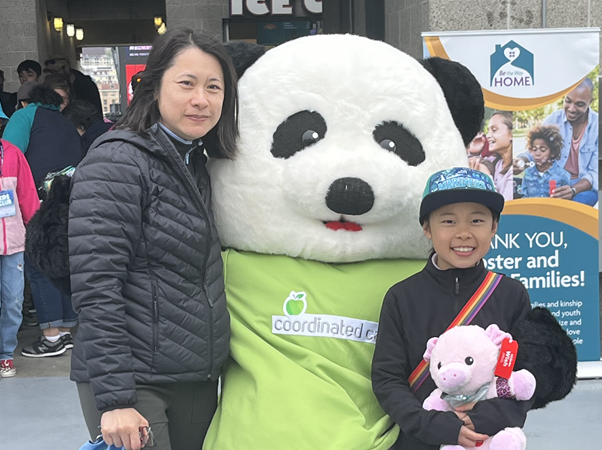 mom and daughter standing with panda mascot, smiling