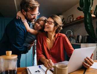 Brief family bonding moment as mom works on laptop at kitchen table