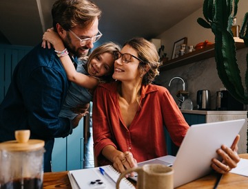 Brief family bonding moment as mom works on laptop at kitchen table