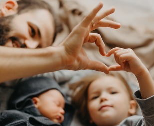 dad and young daughter making a heart shape with their hands. 