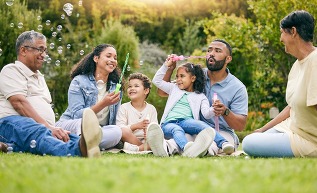 Nature picnic, bubbles and happy family relax, smile or kids enjoy toys, outdoor time together and garden fun.