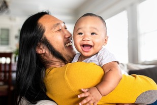 Asian American father hugging his little son