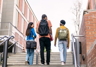 Group of multi ethnic students with backpacks and books ascending university stairs, looking towards a bright future and education