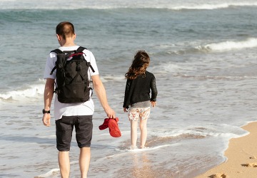 dad and daughter on the beach with their feet in the water