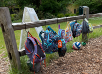 backpacks hanging on a wooden fence