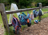 backpacks hanging on a wooden fence