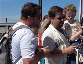 two dads one holding a son, talking to event staff outside