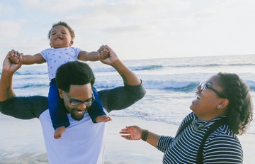 family of three laughing on the beach