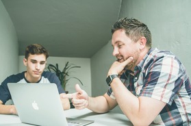 teen and and adult talking with laptop between them