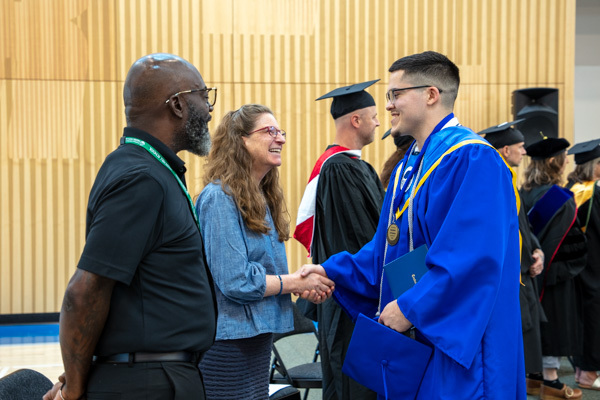 Young person shakes hands with DCYF secretary at Green Hill School graduation. 