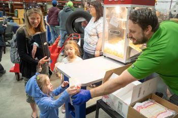 A Surplus worker hands a girl a bag of popcorn at the Grand Re-Opening event. 