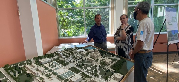 Two architects standing next to a 3D model of the Capitol Campus, explaining building features to a visitor.