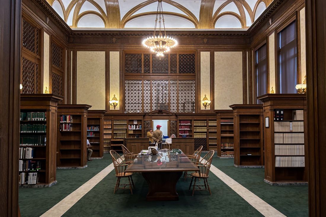 A photograph of the main room of the Law Library shows a patron speaking with librarians at the reference desk.