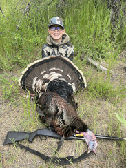 A boy poses with a turkey he has just harvested