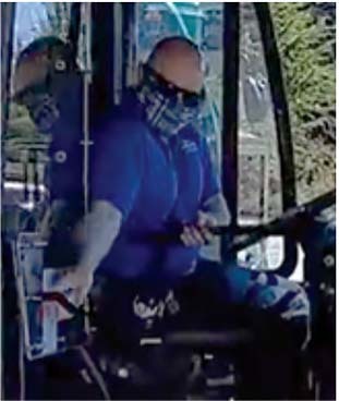 Bus driver wearing a cloth face covering reaching for the handle of a plexiglass shield inside of a bus
