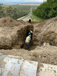 Two workers digging in unprotected trench
