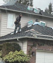 Workers re-roofing a two-story home with no fall protection system in place.