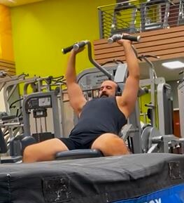 Omid Mohammadhi Dashti, workers' comp theft defendant, pushes up on weight machine, in fitness center in Renton, in November 2023.