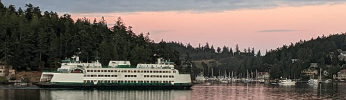 Ferry boat on Sound with trees in background at sunset