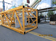 A section of the collapsed tower crane laying in the street in front of a glass building.